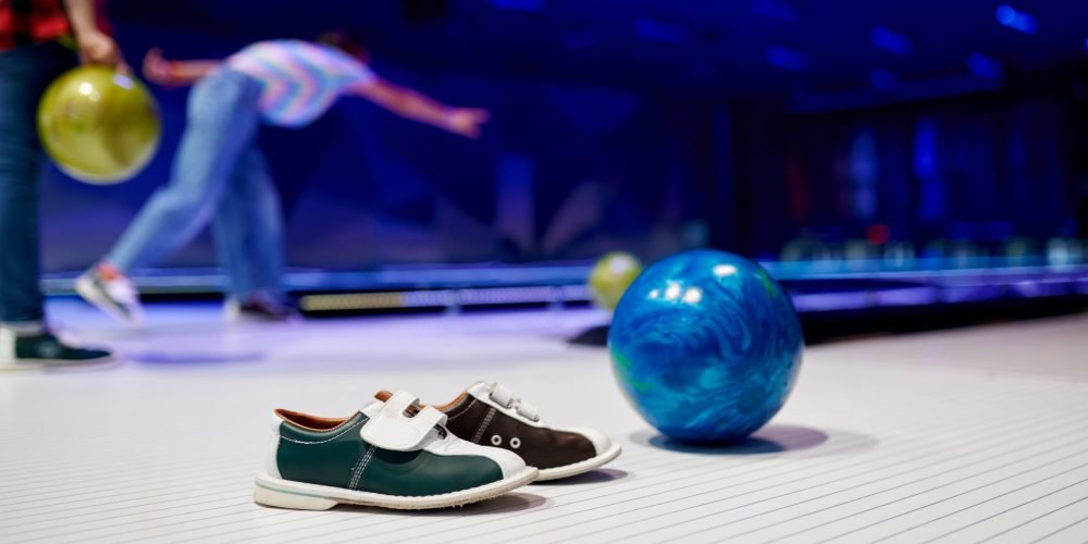 Ball and house shoes, children playing bowling, game concept. Kids are preparing to score a strike. Boys and girls having fun in entertainment center together
